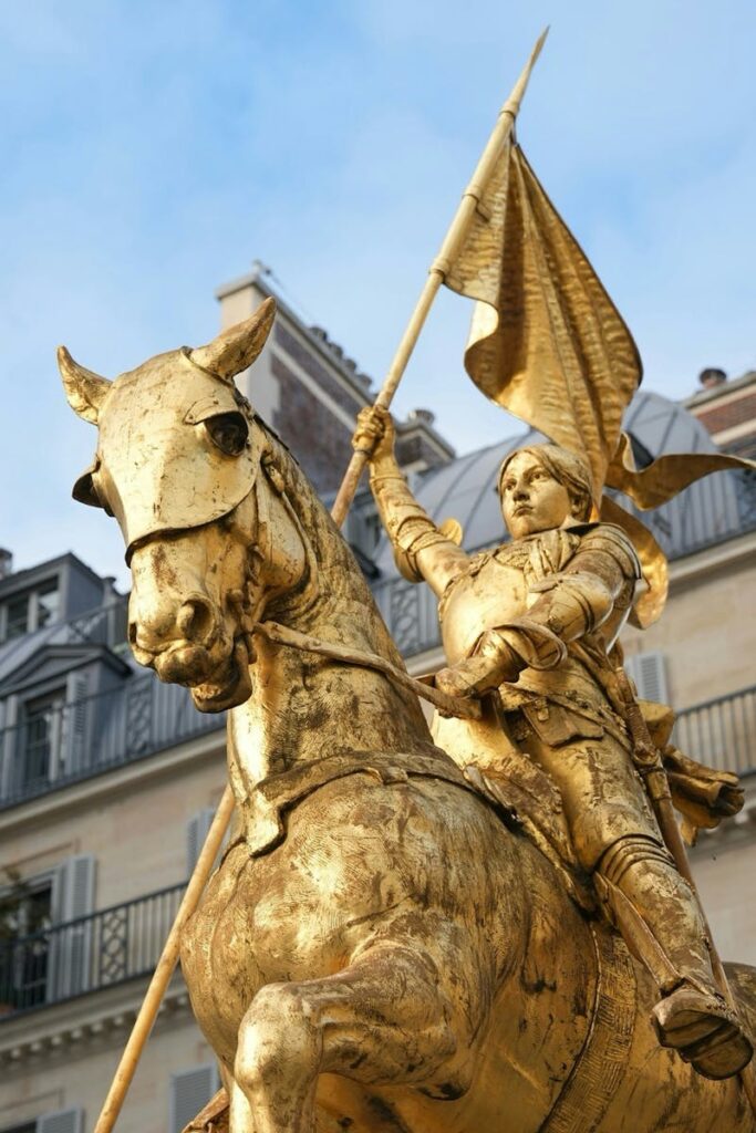 Golden equestrian statue of Joan of Arc in sunny Paris setting.