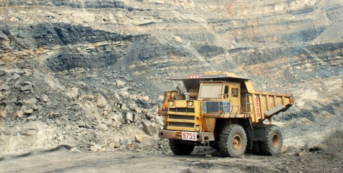 A large yellow mining truck in a rocky quarry under a clear sky.