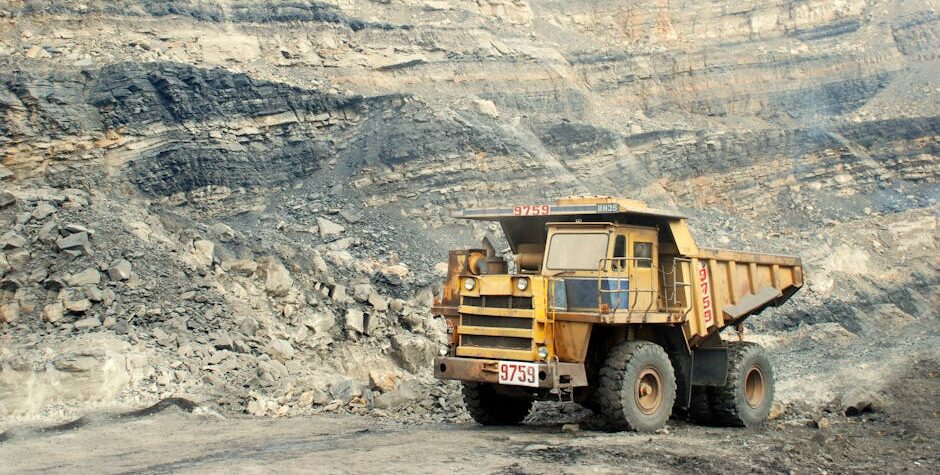 A large yellow mining truck in a rocky quarry under a clear sky.