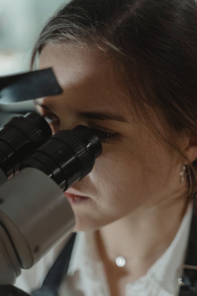 Close-up of a female scientist using a microscope in a laboratory setting.